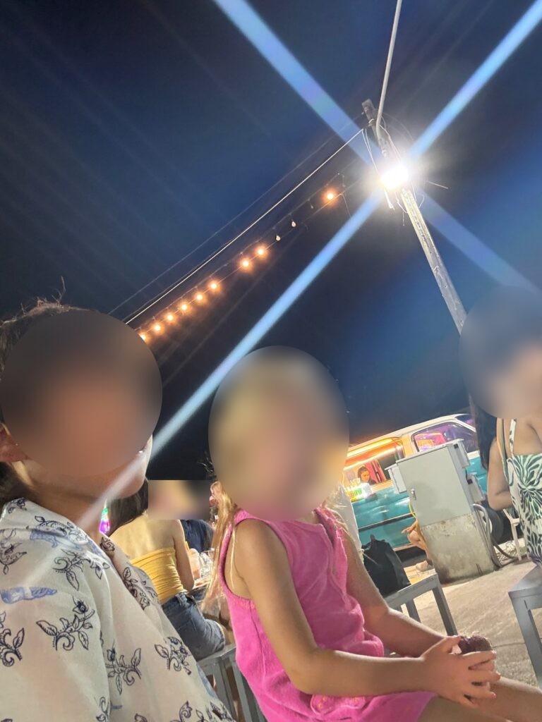 전구 줄 아래 야시장 의자에 앉은 아이들
